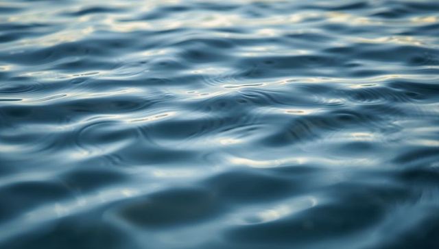 Rippling teal water surface with soft sky reflections and gentle wavelet texture