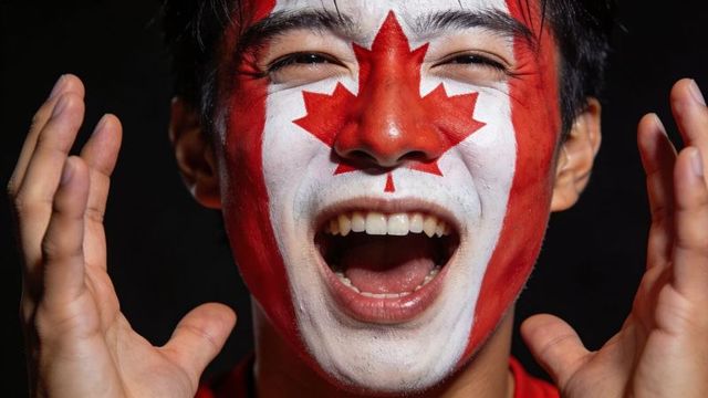 Asian fan cheering with canada maple leaf face paint, close-up portrait, raising hands