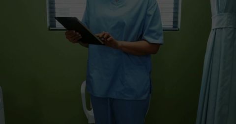 Healthcare Professional in Scrubs Using Tablet for Patient Care