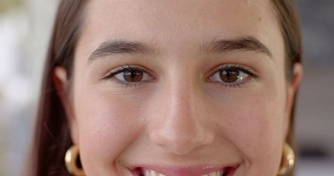Close-up portrait of smiling woman with gold hoop earrings