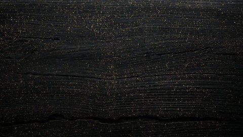 Black wood panel featuring horizontal grain and gold flecks for elegant luxury background