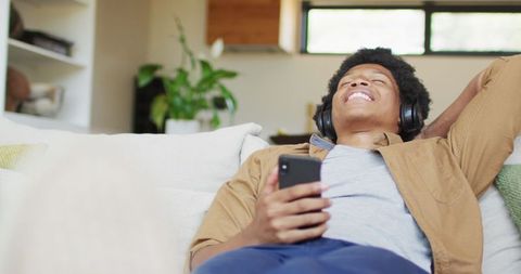 Relaxed Man Enjoying Music with Smartphone and Headphones at Home