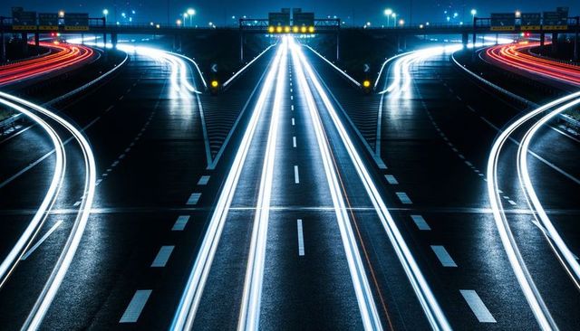 Symmetrical long-exposure light trails on multilane freeway interchange at night