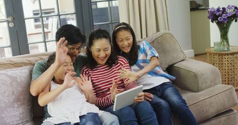 Happy Asian Family Enjoying Tablet Together on Couch