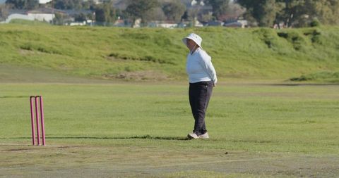 Female Cricket Player Standing on Field in Oversized Hat