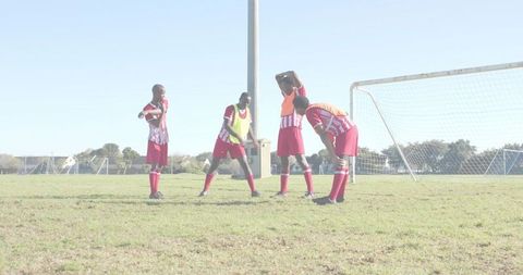 Youth soccer players preparing throw-in near goal on sunny suburban field