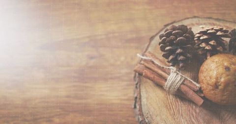 Rustic autumn still life featuring pinecones, cinnamon sticks and baked muffin on wood slab