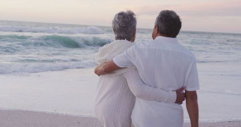 Senior Hispanic Couple Embracing on Beach at Sunset
