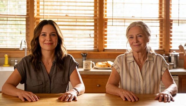 Mother daughter sharing calm morning at sunlit kitchen table, hands resting