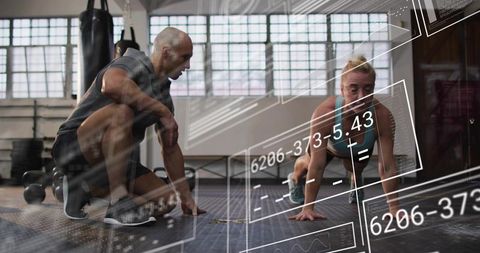 Personal trainer coaching female athlete performing plank with virtual hud fitness data