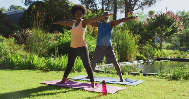 African american senior couple exercising practicing yoga standing in sunny garden. staying at home in isolation during quarantine lockdown.