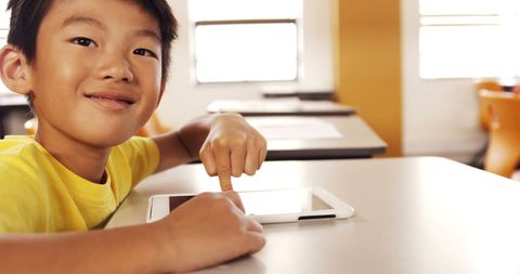 Smiling boy engaging with tablet in classroom setting