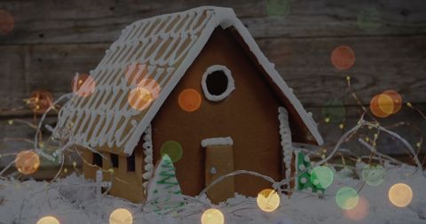 Festive bokeh lights with a gingerbread house on snow