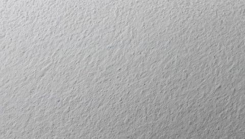 Textured gray plaster surface revealing subtle bumps and fine grain under soft light