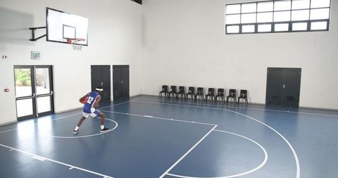Young athlete practicing basketball on indoor court