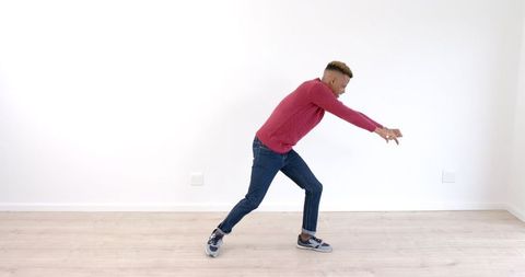 Energetic young man dancing inside bright minimalist room