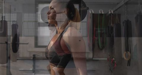 Woman lifting barbell overhead in gym demonstrating strength