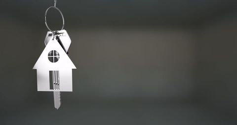 House-shaped keychain with key over subtle background