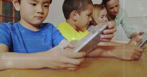 Teacher Assisting Children Using Tablets for E-Learning in Classroom