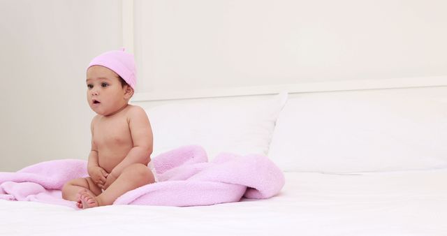 Cute baby with pink cap sitting at home