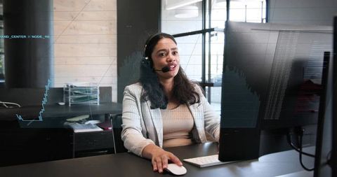 Customer support specialist wearing headset working at desktop with financial charts