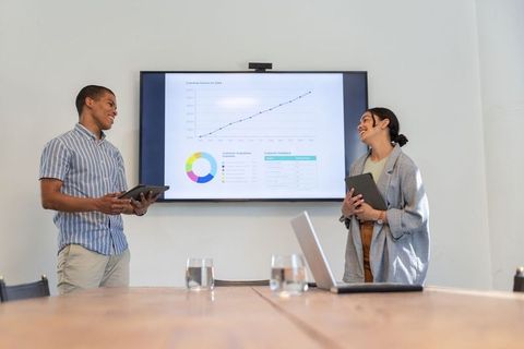 Diverse Colleagues Presenting Data with Tablets and Screen in Office