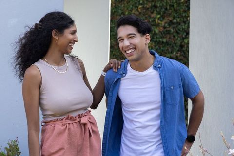 Laughing couple sharing joyful moment outdoors in casual summer style with gold jewelry