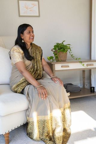 Mature indian woman in traditional saree sitting in elegant living room