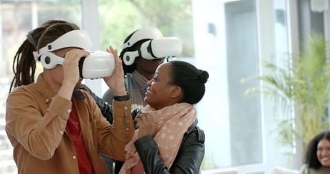 Diverse team testing white VR headsets in modern bright office lounge for collaboration