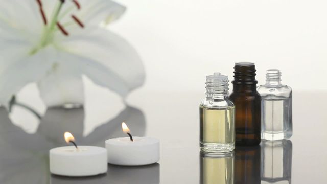 A relaxing scene featuring lighted candles and small bottles of essential oils, indicative of a tranquil spa environment. Ideal for wellness blogs, skincare advertisements, or aromatherapy guides to evoke a sense of calm and beauty.