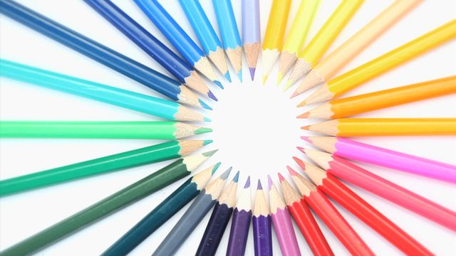 Top view of brightly colored pencils arranged in a circular pattern on a white backdrop. Excellent for use in educational materials, creativity and art product promotions, or design-related content. Conveys a sense of creativity and artistic expression.