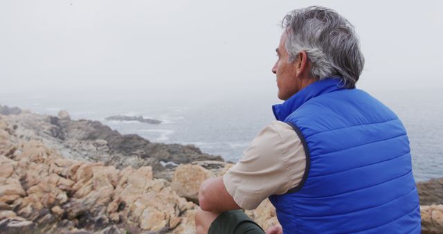 Senior Man Enjoying Ocean View from Rocky Shore on Foggy Day - Download Free Stock Images Pikwizard.com