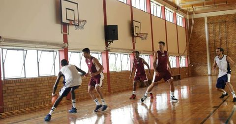 Point guard dribbling and driving past defenders on indoor hardwood court during game
