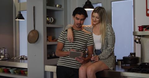Happy Couple Relaxing in Modern Kitchen Using Digital Tablet