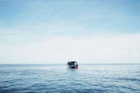 Lonely Fishing Boat on Calm Sea with Peaceful Horizon