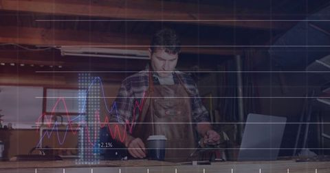 Woodworker reviewing analytics overlay at bench wearing apron with laptop and tools