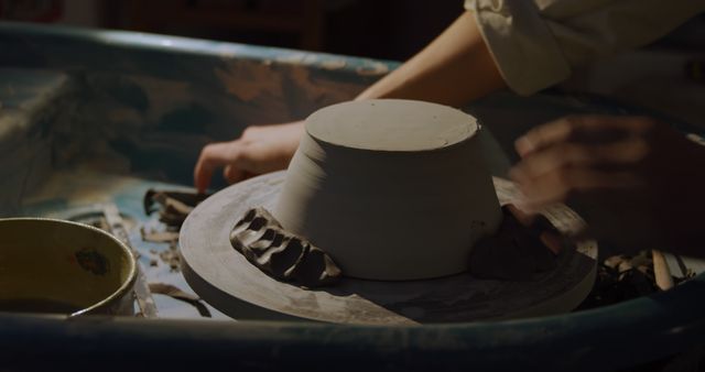Hands shape clay on a pottery wheel in a workshop. The focus on the creative process highlights the art of pottery making.