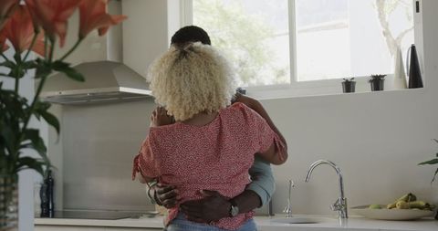 Couple Embracing in Kitchen with Engagement Ring Surprise