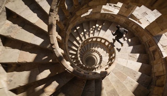 Descending Man on Historic Spiral Stone Staircase Creating Dramatic Depth and Motion