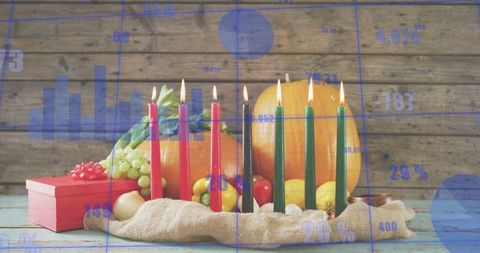 Celebrating kwanzaa with kinara: seven lit candles on rustic wooden tabletop with pumpkins