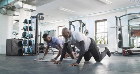Knee push-ups for partner strength training, two men doing calisthenics in gym