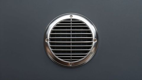 Circular stainless steel ventilation grille on wall