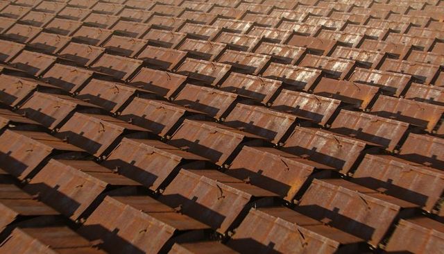 Rusted Metal Roof Tiles Creating Repetitive Geometric Pattern with Patina and Shadows