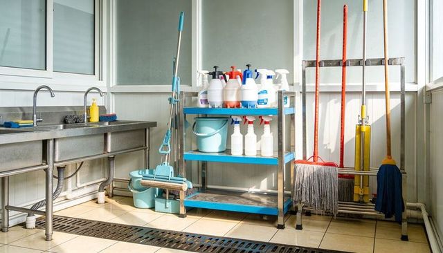 Organized commercial cleaning cart with mops buckets and disinfectants in utility room