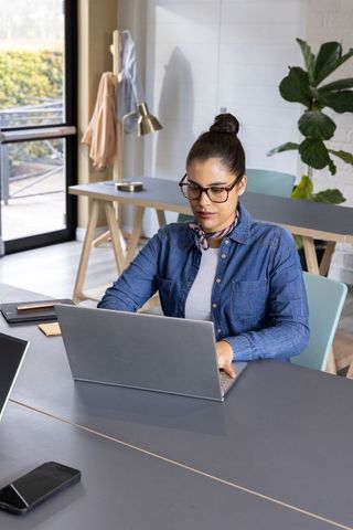 Focused young professional working on laptop in modern coworking space with minimal decor