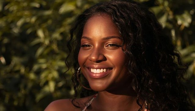 Radiant african american woman smiling in golden hour garden light, hoop earring portrait