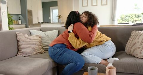 Close friends embracing on cozy sofa in bright modern living room