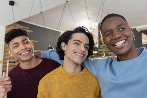 Diverse young men laughing and posing by pool table in modern lounge wearing sweaters