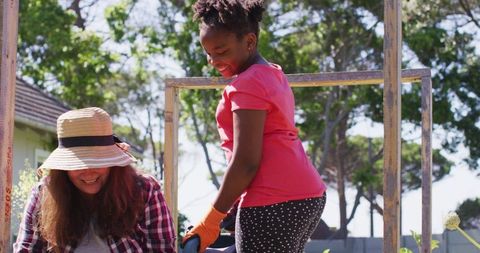 Mother and Daughter Joyfully Gardening in Sunlit Backyard