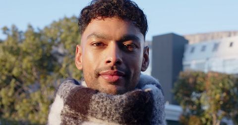 Asian Man Wearing Fuzzy Checkered Scarf on Urban Rooftop Portrait in Golden Sunlight